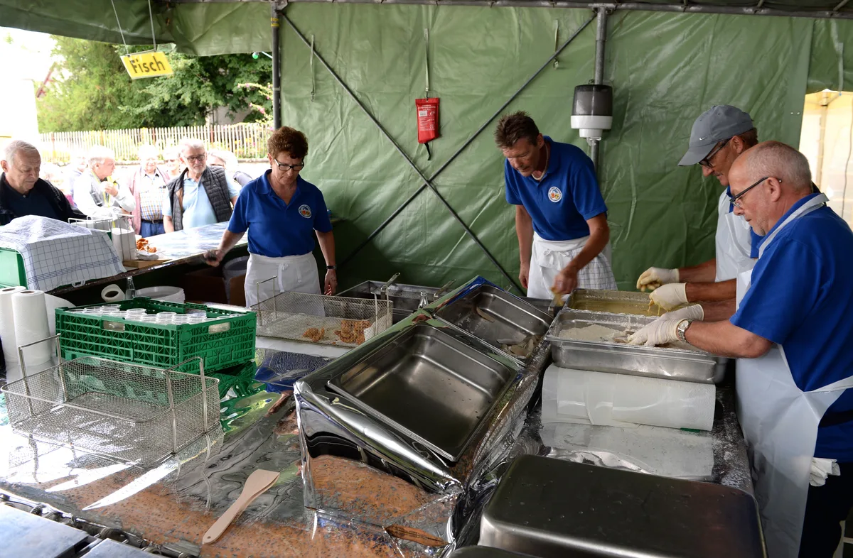 Menschen, die Zanderfilets im Bierteig frittieren.